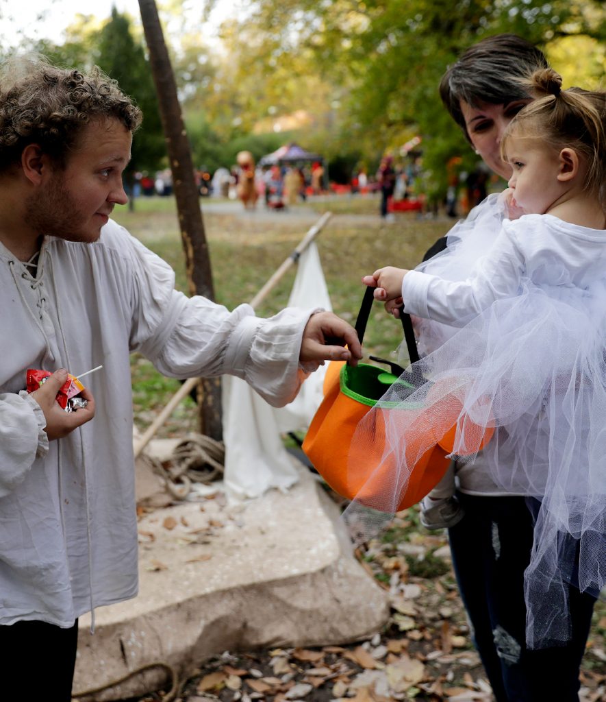 a man handing a child candy for halloween in the zoo